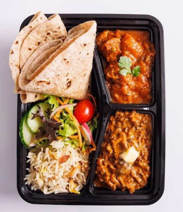 Tiffin box with curries, rice, chapatis and salad